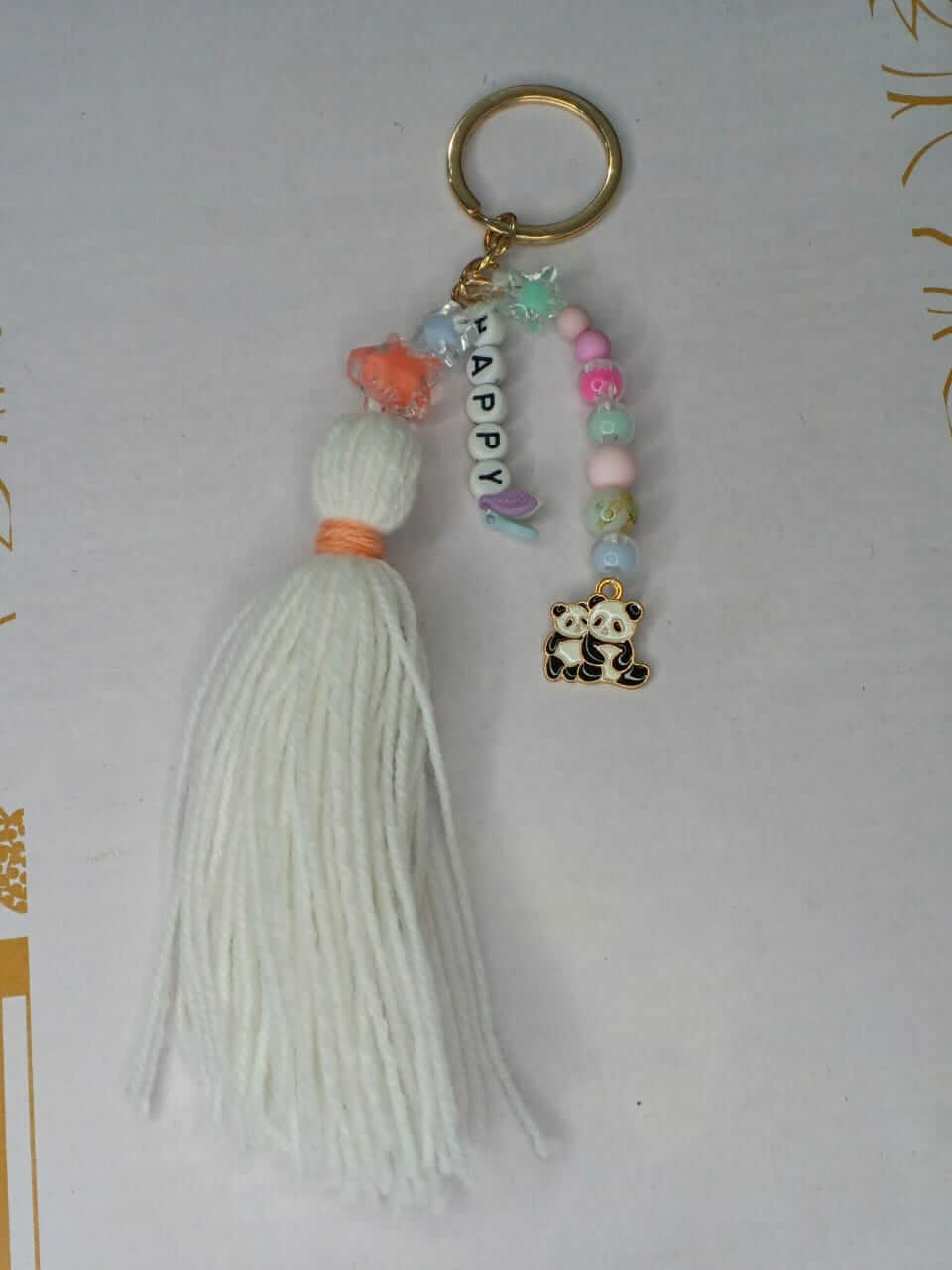 Keychain with tassel, panda charm, and 'Happy' beads on a light background