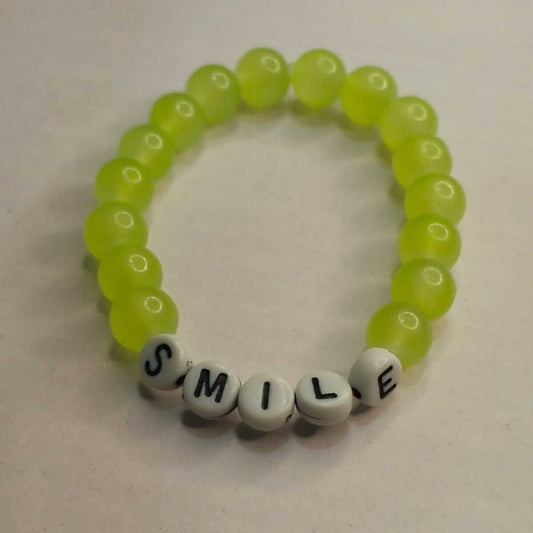 Neon green beaded bracelet with letter beads spelling 'SMILE' on a light background